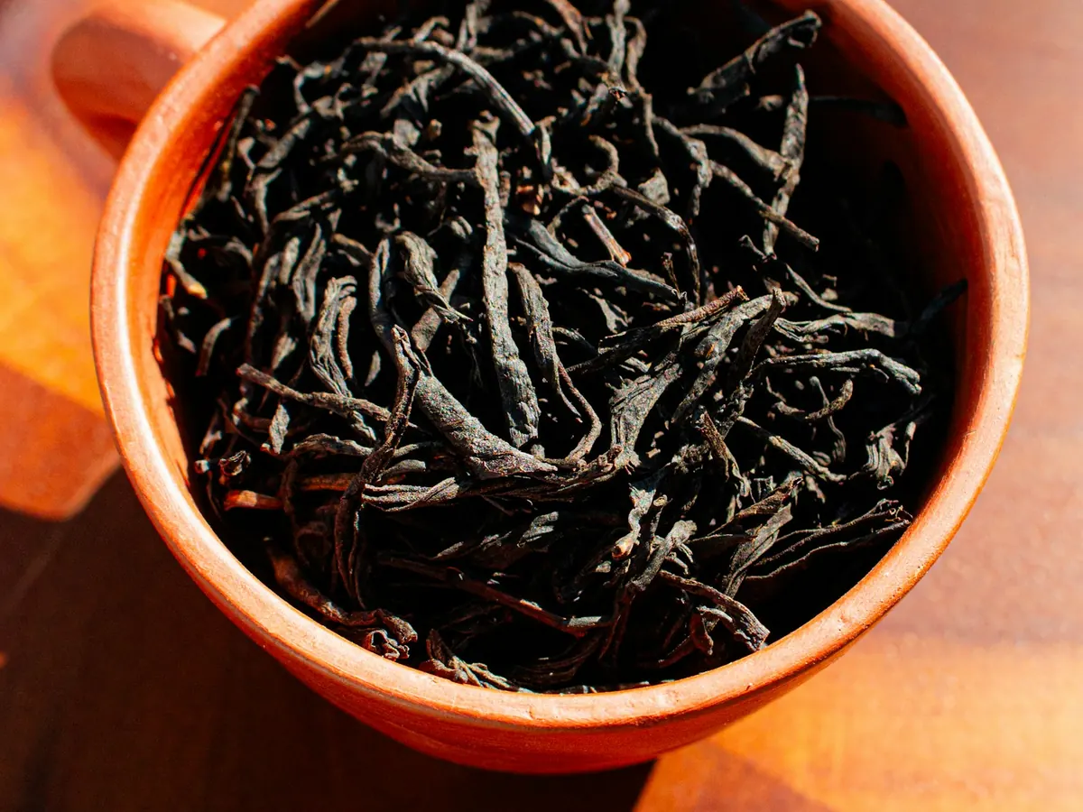 Dried whole-leaf black tea in a terracotta bowl